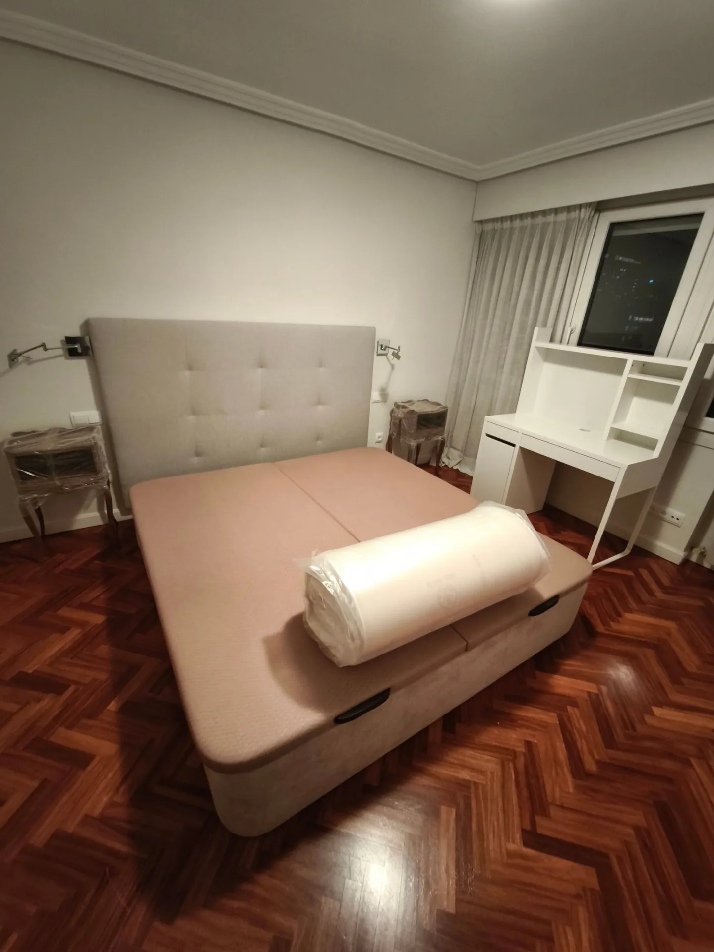 Cama canapé con cabecero tapizado y escritorio blanco en un dormitorio