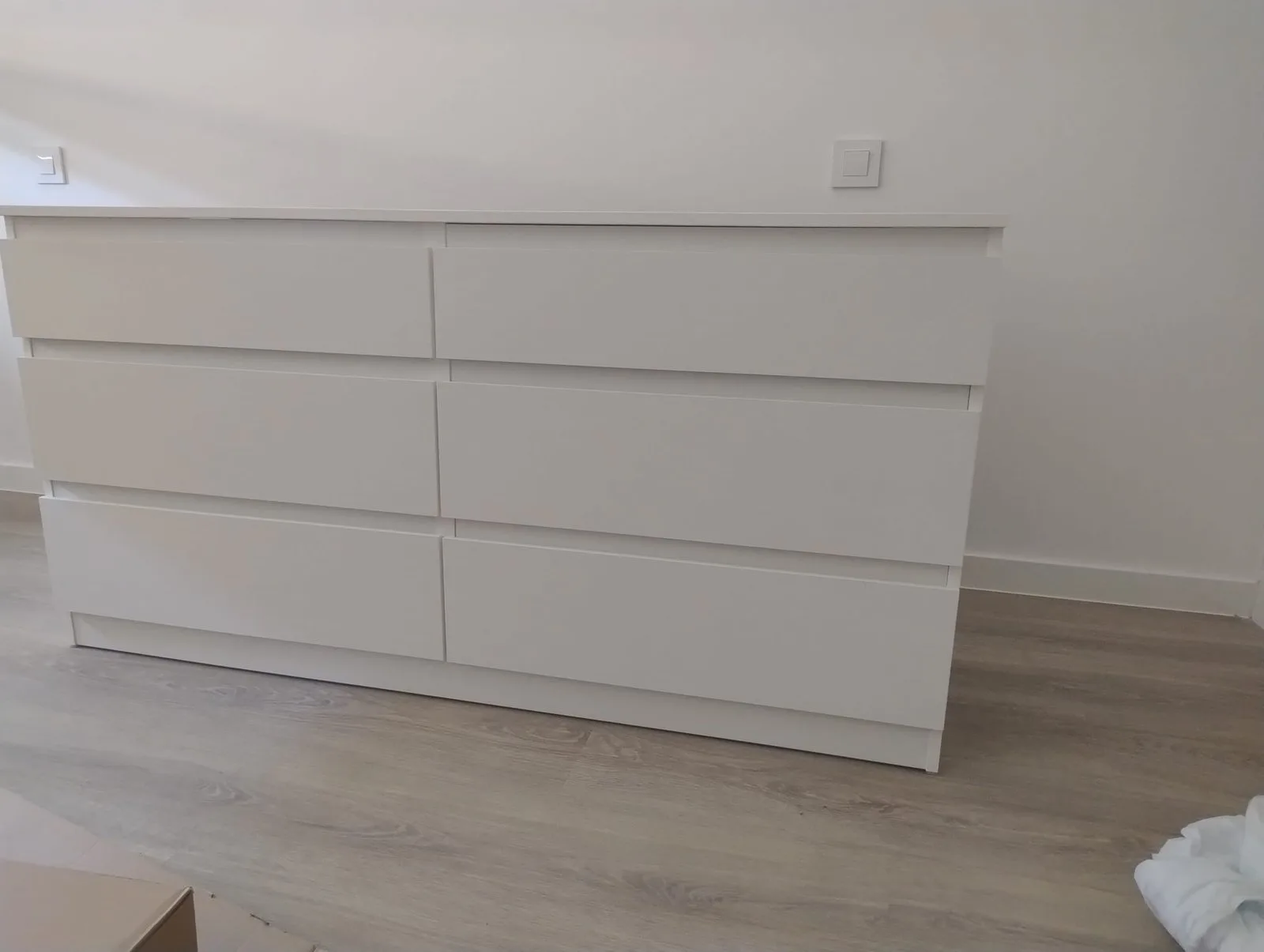 Cómoda blanca de seis cajones montada contra la pared