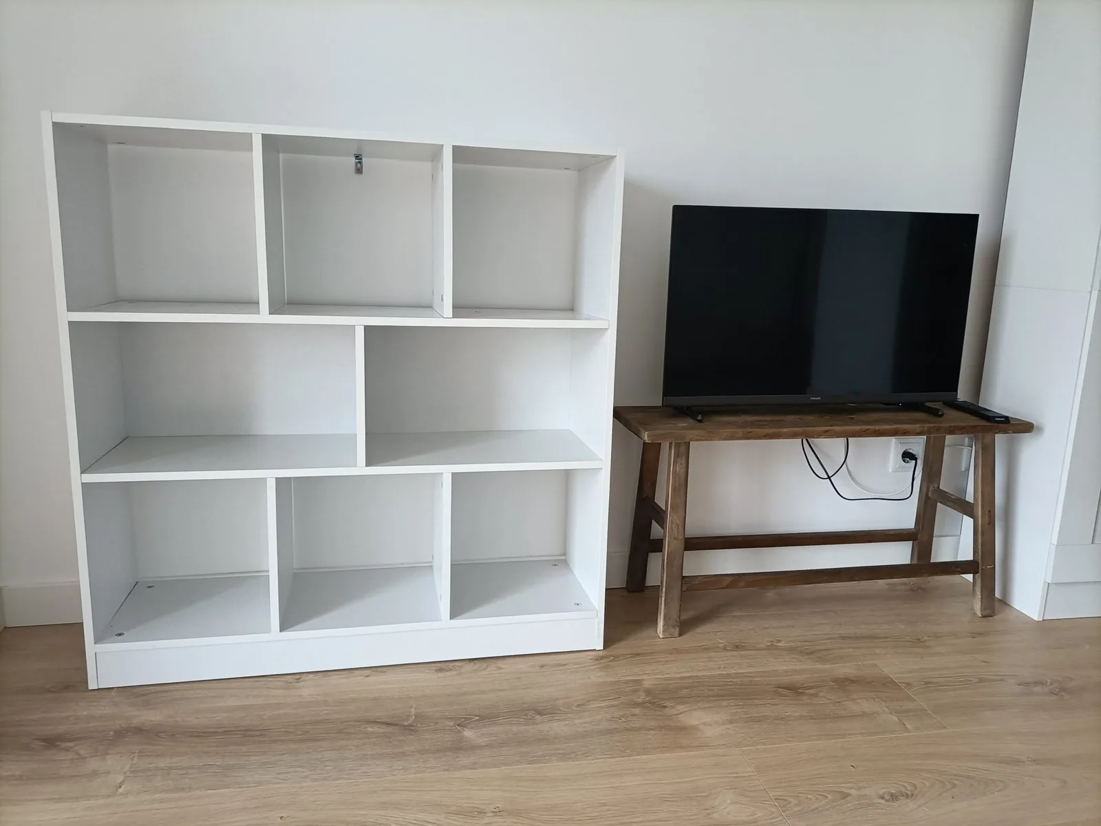 Estantería blanca de cubos junto a un mueble de TV montados en un salón