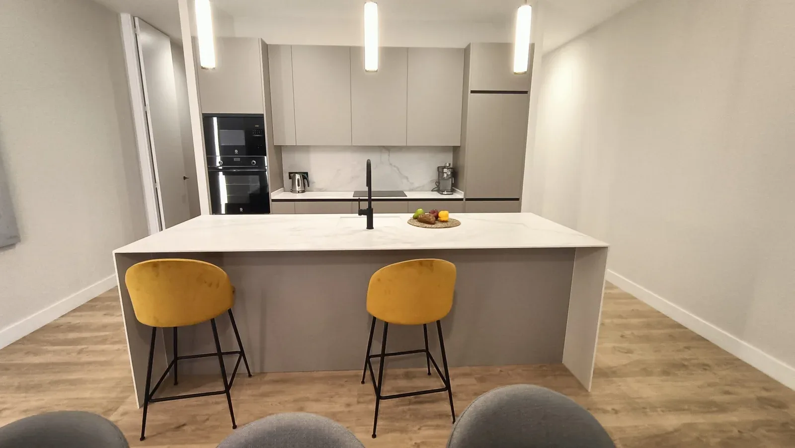 Cocina con isla y taburetes en piso de alquiler