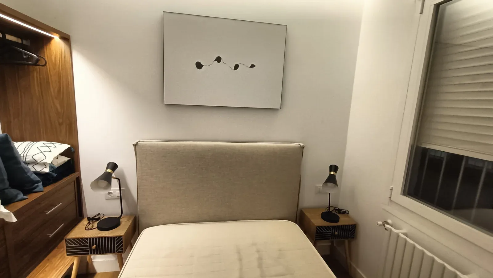 Dormitorio con cabecero tapizado y mesitas