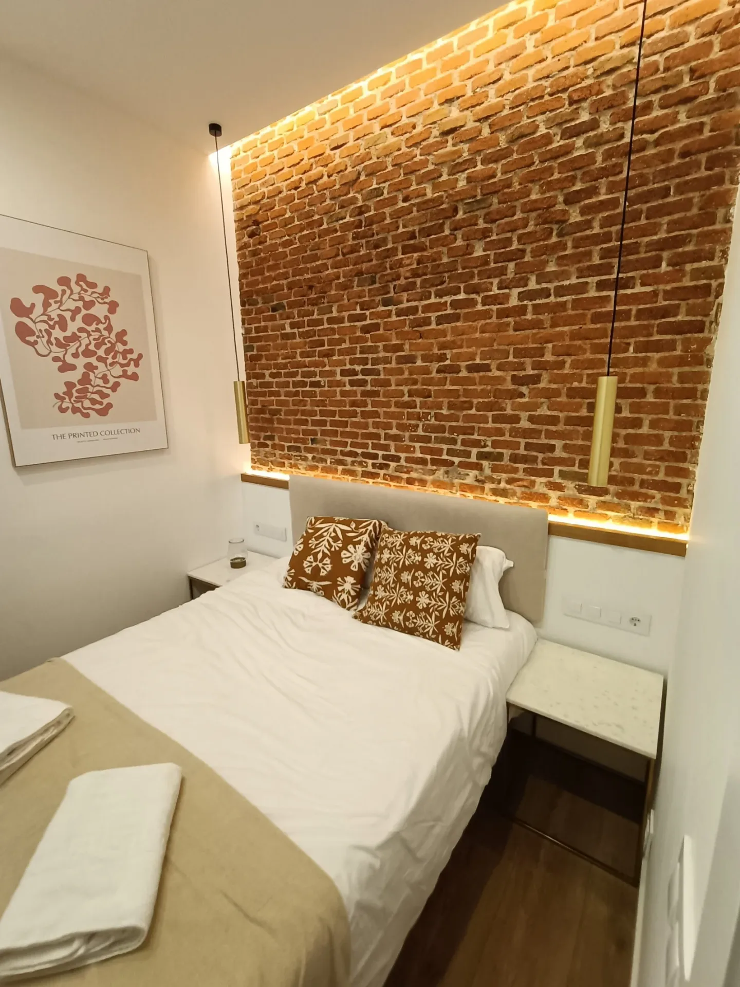 Dormitorio con pared de ladrillo visto y cama montada