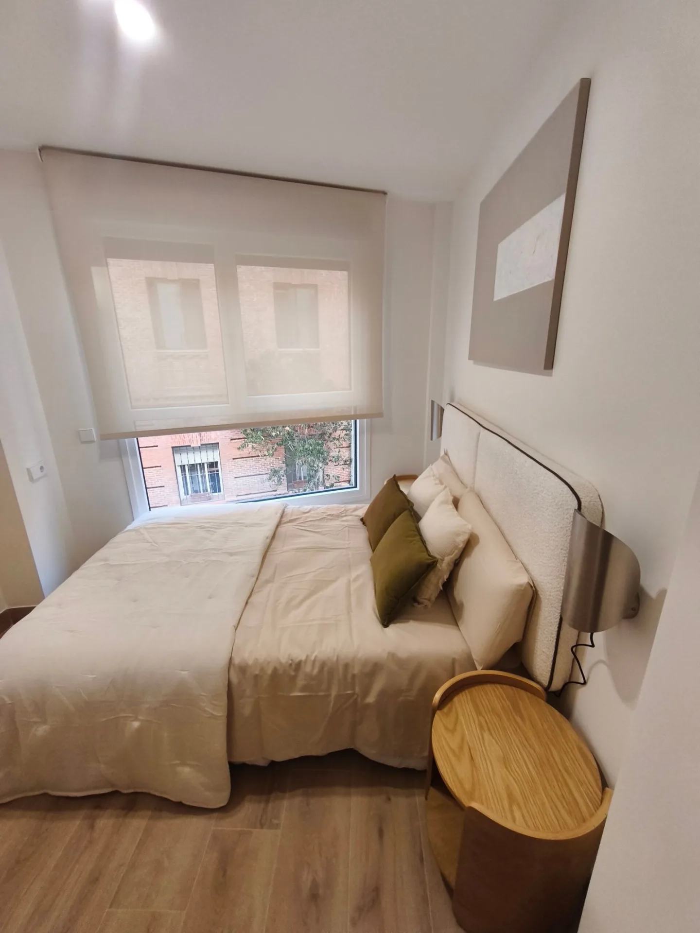 Dormitorio amueblado con cama doble, cabecero tapizado y mesitas de noche