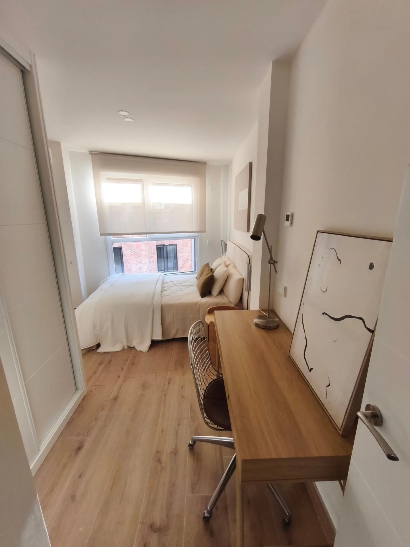 Dormitorio con escritorio de madera, silla y cama de matrimonio