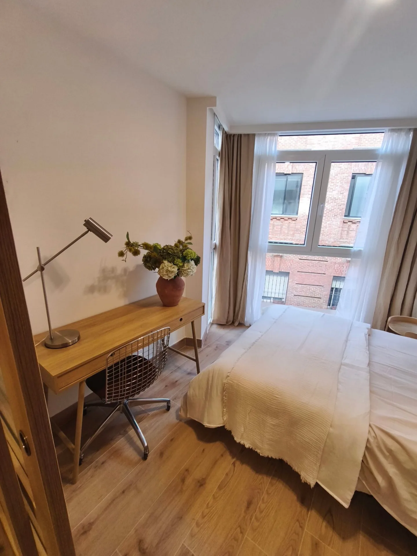 Escritorio de madera con lámpara y silla junto a la cama en un dormitorio