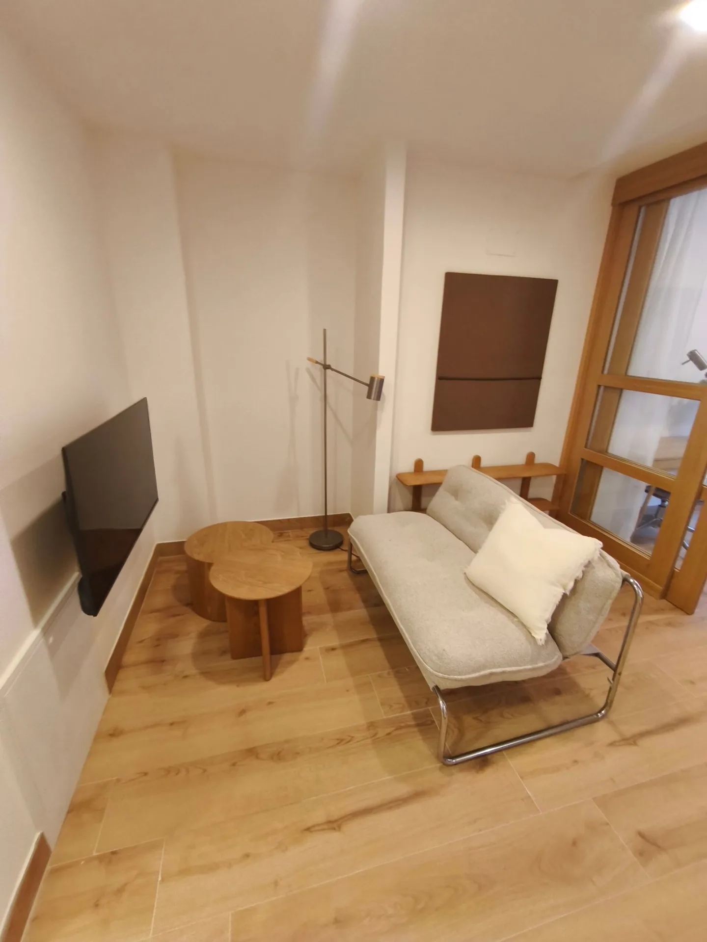 Salón con sofá, televisor en la pared y mesa de centro de madera