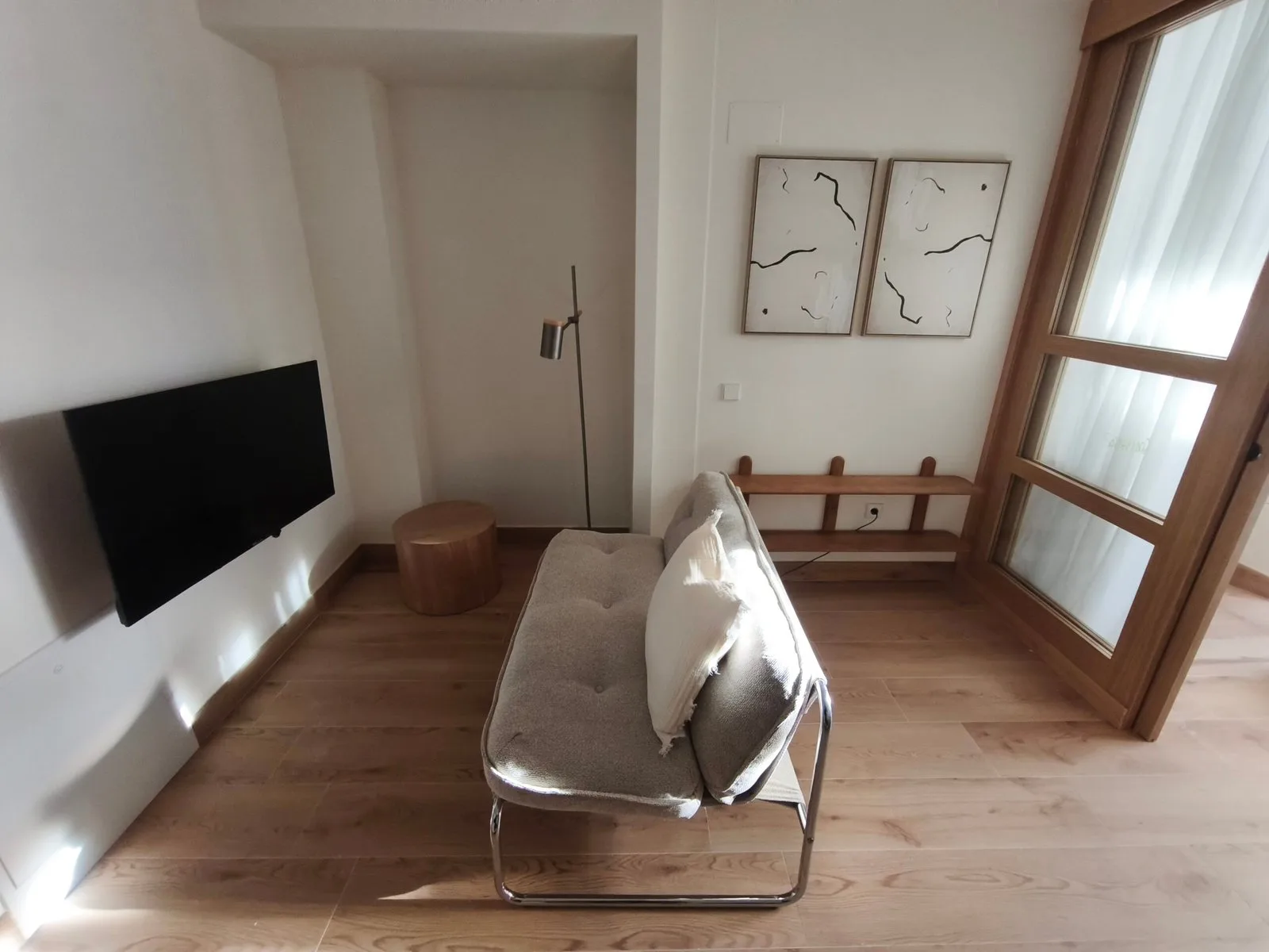 Salón pequeño con sofá y televisor colgado en la pared